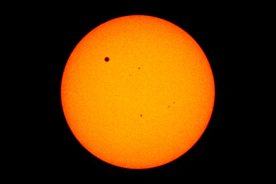 这是国际空间站(ISS)上的宇航员于2012年6月6日拍摄的金星凌日照片。在照片中可以看到，金星周围有一圈黑色圆环，在照片中央还可以看到几颗太阳黑子。