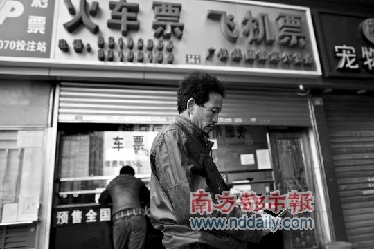 梅丽路一车票代售点,工人向先生买不到前往昆明的车票,欲打电话向朋友求助。南都记者赵炎雄摄
