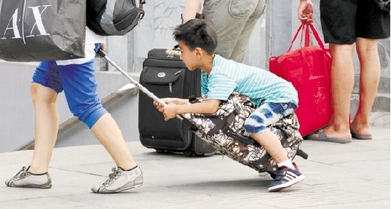 昨天,火车东站广场,一位小朋友不想走路就骑到了行李上让大人拖着走.