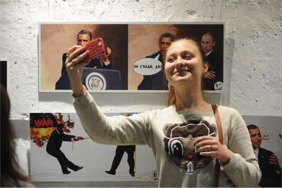 一名俄罗斯女子与身后的普京与奥巴马PK漫画合影