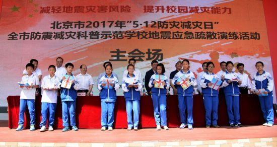 与会领导向学生代表授书 5·12防震减灾应急疏散演练在北京举办
