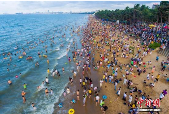 中国传统节日端午节,海南省海口市假日海滩景区汇集众多民众“洗龙水”。(航拍图) 中新社记者 骆云飞 摄 海口“内外兼修”力促“城市更新”
