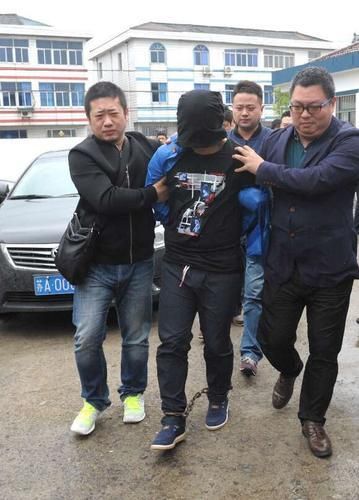 嵇仁兵(戴头套)被押解回南京警方供图