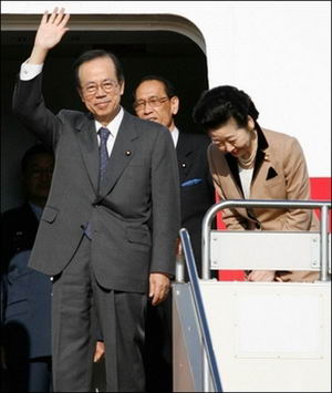 图为2007年12月27日,日本首相福田康夫在东京羽田机场挥手告别,即将