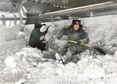 消防战士在商都受暴雪围困的旅客列车下除雪抢险.