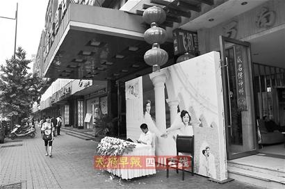 比起婚礼的热闹,酒店门口印有新郎新娘婚纱照