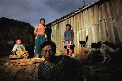 云南省开远市红坡头村，吴笑林一家在自己的棚屋前。他们一家和村里大多数人一样都没有户口，不能外出务工，只能靠种地过活，全家年收入5千元左右。当地每户人家都有好几个孩子，住简陋的棚屋，生活水平非常低。