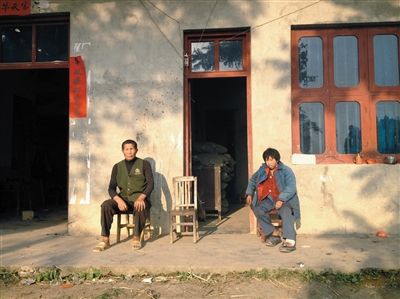 5月2日，艾绍金（左）和有“智障”的二嫂王春娥坐在家门口。新京报记者 刘刚 摄