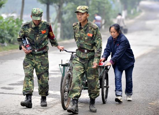 图文:两位解放军战士在帮助受灾群众运水