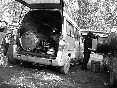 11月4日，昌平区赖马庄村，废机油回收黑市的大院内，正在从油桶向小桶里倒油。面包车上配置油桶和油泵,是小贩外出收油的专用装备。