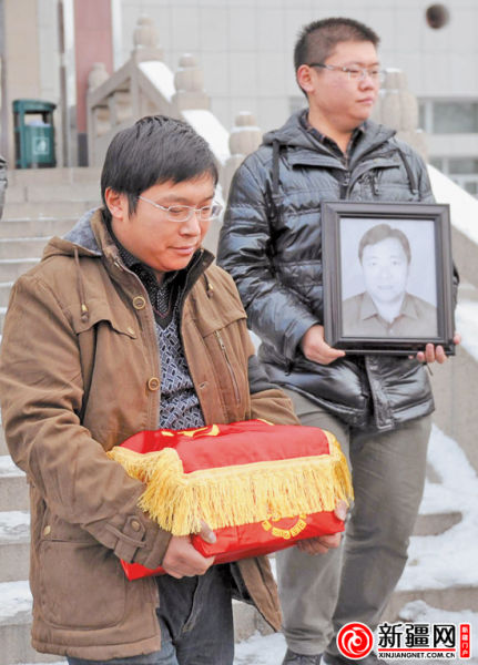 12月7日,在乌鲁木齐市殡仪馆,徐勇(左)抱着父亲徐胜利的骨灰盒送父亲