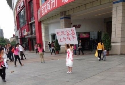 白布女广场举牌讨孩子 称嫁富二代遭家暴(图