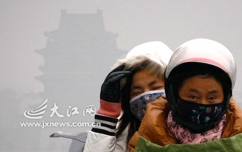 南昌昨日又是一片灰蒙蒙，滕王阁落隐落现，市民纷纷戴上口罩出行。记者李伟摄