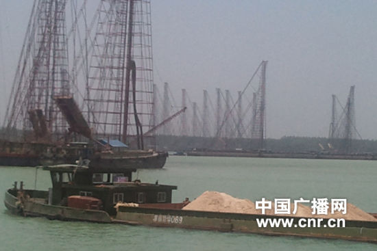拉沙船从数量众多的采砂船旁经过。