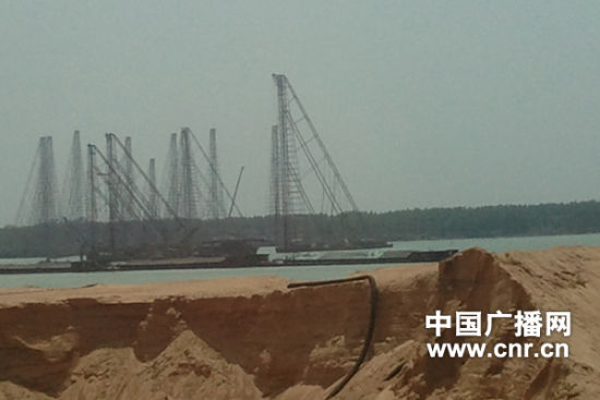岸边的堆砂场，不远处就是数量众多的采砂船。
