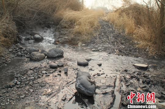 章村矿南风井排水口排出的废水将周围石头染成黑色。　肖光明　摄