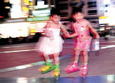 夜晚的南京路步行街充满动感和激情,两个脚穿旱冰鞋的小女孩在世纪