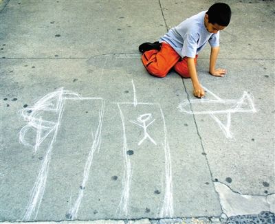 在纽约的克里斯托弗和韦弗利街区,一名小男孩用石头在地上画出飞机