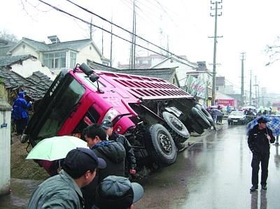 侧翻的运沙车压住门面房。 任国勇 摄