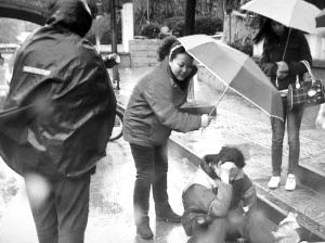 孕妇（左二）杨燕顾不上自己被淋湿，为地上的华奶奶撑伞 报料人供图