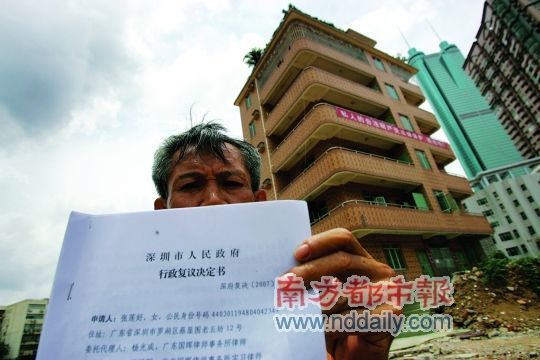 2007年10月2日，蔡珠祥拿着深圳市政府行政复议书，1700万元补偿款已经到账，后面就是他坚守多时的房子。南都记者王子荣摄（资料图片）