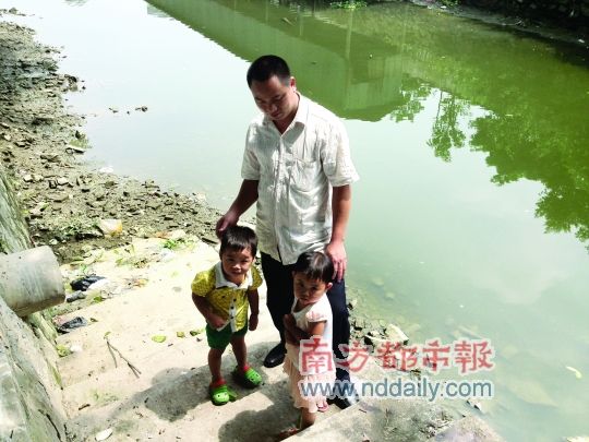 叶锡坤带着两名被救的小孩再次来到河涌边，此时水位已经下降1米多。