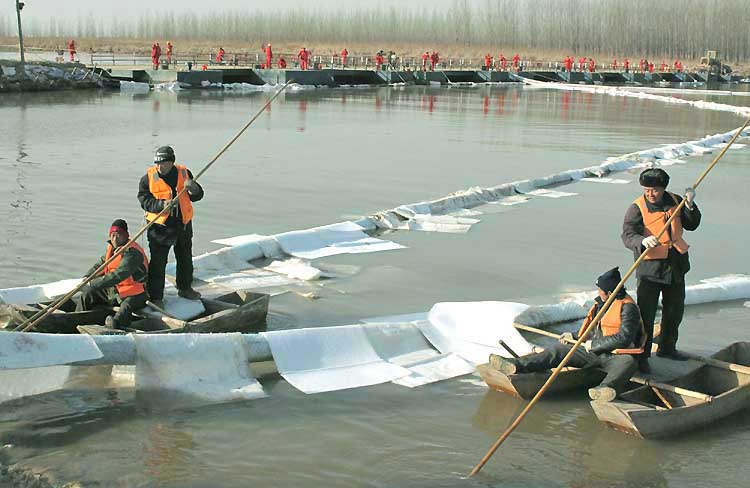 图文:工作人员在河面上抛洒凝油剂抢险收油
