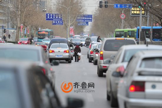 在济南市经十路与历山路路口，每天早晨，一位弯腰驼背的老奶奶都会出现在早高峰的车流中 （记者 张晓博 摄）