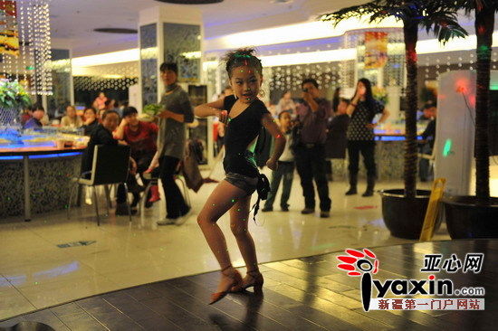 10月26日，演出台上黄豆豆正在给来这里吃火锅的消费者跳拉丁舞，艳丽的服饰和妆容和她这个7岁的年龄有点不相符合。亚心网记者 李远新 摄