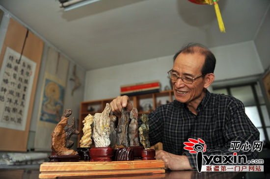岳恩荣把玩着自己一生的宝藏——奇石画。亚心网记者 赵宇飞 摄