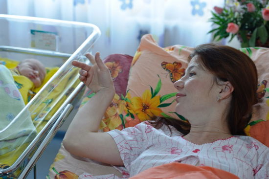 10月31日，俄罗斯加里宁格勒市地区妇产中心内，母亲叶莲娜·尼古拉耶娃看着刚刚出生的小彼得熟睡。新华社记者 姜克红 摄