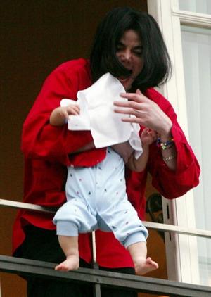 Singer Michael Jackson is pictured holding a child out of a window as he looks at fans after arriving at a Berlin hotel, in this November 19, 2002 file photo. [Agencies]