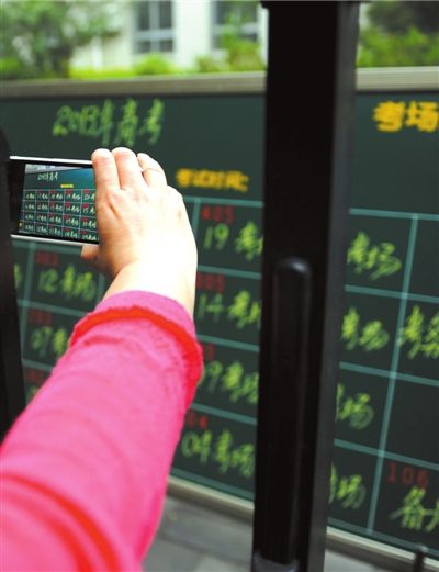 昨天，在北京市第四十四中学，一名考生家长用手机拍下考场分布图。 京华时报记者 徐晓帆 摄影报道