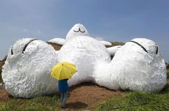A person stands in front of a 25.3-meter-long giant rabbit designed by Dutch artist Florentijn Hofman at an old aircraft hangar as part of the Taoyuan Land Art Festival in Taoyuan, northern Taiwan, Sept 3, 2014. [Photo/Agencies]