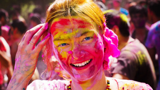 A woman has coloured powder applied to her face during celebrations of Holi, the festival of colours