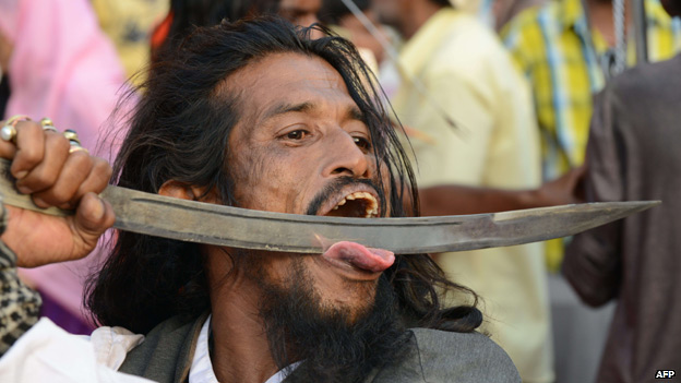 A man pushes a sword across his tongue