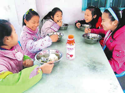 在广西融水苗族自治县香粉乡中心小学，一群六年级的小学生围坐在食堂里，吃着香喷喷的“免费午餐”。