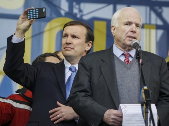 Sen. Chris Murphy (D-Conn) left, takes a photograph as Sen. John McCain (R-Ariz) makes a speech to pro-European integration protesters in Kiev Sunday.