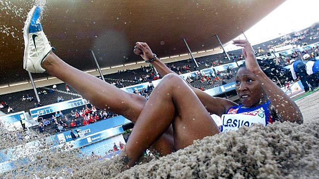 A female long jumper lands in a sandpit