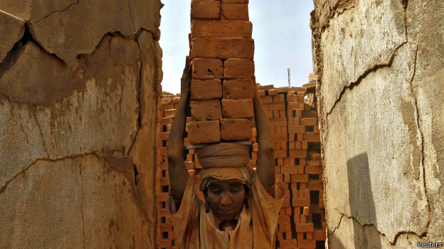 A woman carries bricks on her head in India