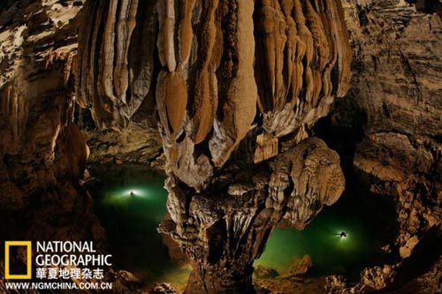 In the Hang Ken cave, flow stone formation of huge hole column stands, below the explorers swimming through the deep pool. Hang Ken is one of the 20 caves discovered last year in vietnam.