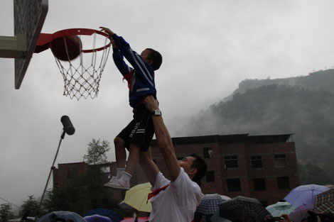 Yi Jianlian helps child dunk at sports facility dedication