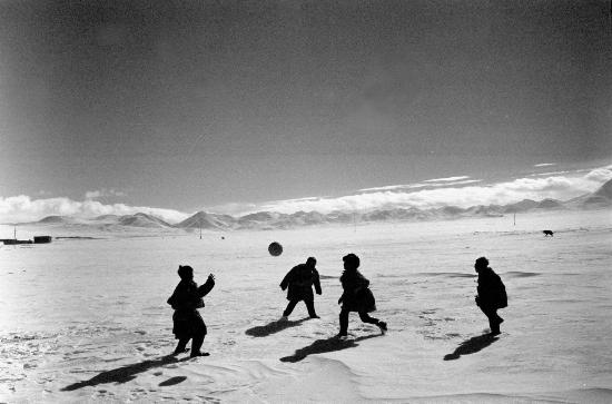 图为1990年冬,西藏纳木错边的孩子们在雪地上踢足球.