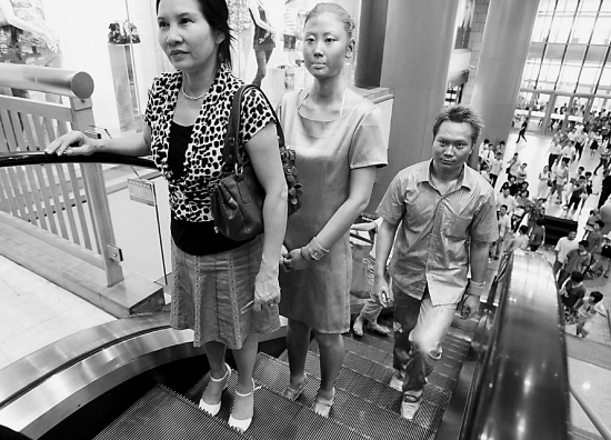 在浦东正大广场,两位全身涂满金粉和银粉的活体雕塑,倡导"左行右立"