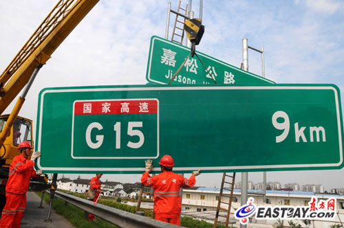 图为工作人员正在沪宁高速江桥出口处对指路标志进行更换