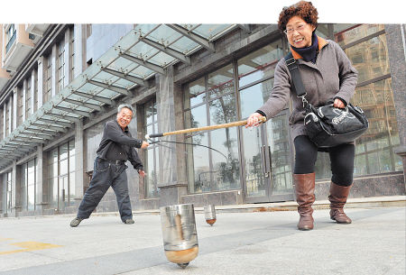 浏阳河风光带旁,两个老人挥舞着长鞭抽打着陀螺.