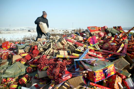 图文:工作人员在向伪劣假冒烟花爆竹上洒汽油