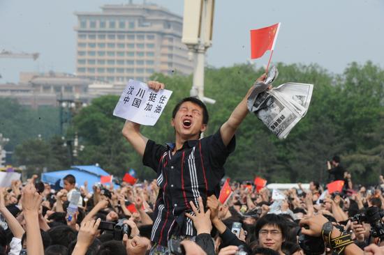 图文 一名男子手举汶川挺住的牌子高呼加油