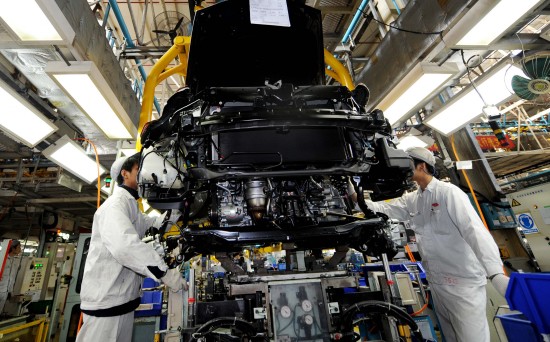 12月24日,广本汽车公司的工人在流水线上安装发动机