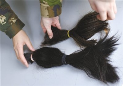 两名新兵向记者展示自己剪掉的长发,由于部队规定,女兵不能留过肩长发